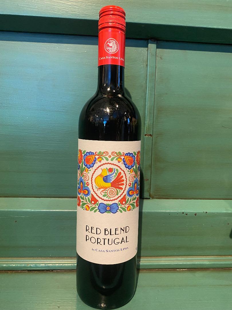 Bottle of red wine with a colorful label on a green wooden surface