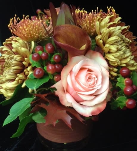 Compact autumn-toned arrangement with a peach rose, bronze blooms, and berries in a brown vase