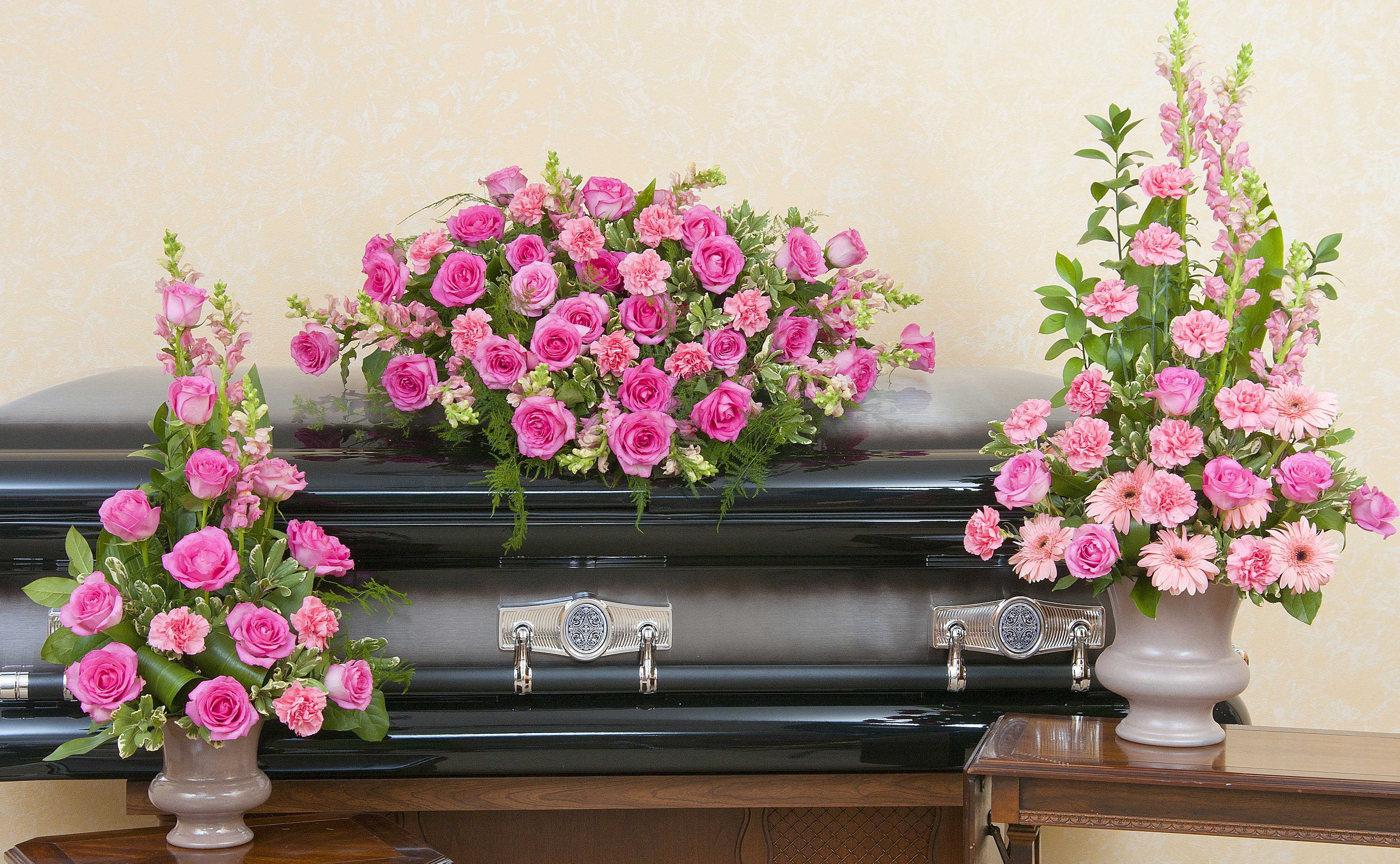 Pink floral sprays arranged around a black casket