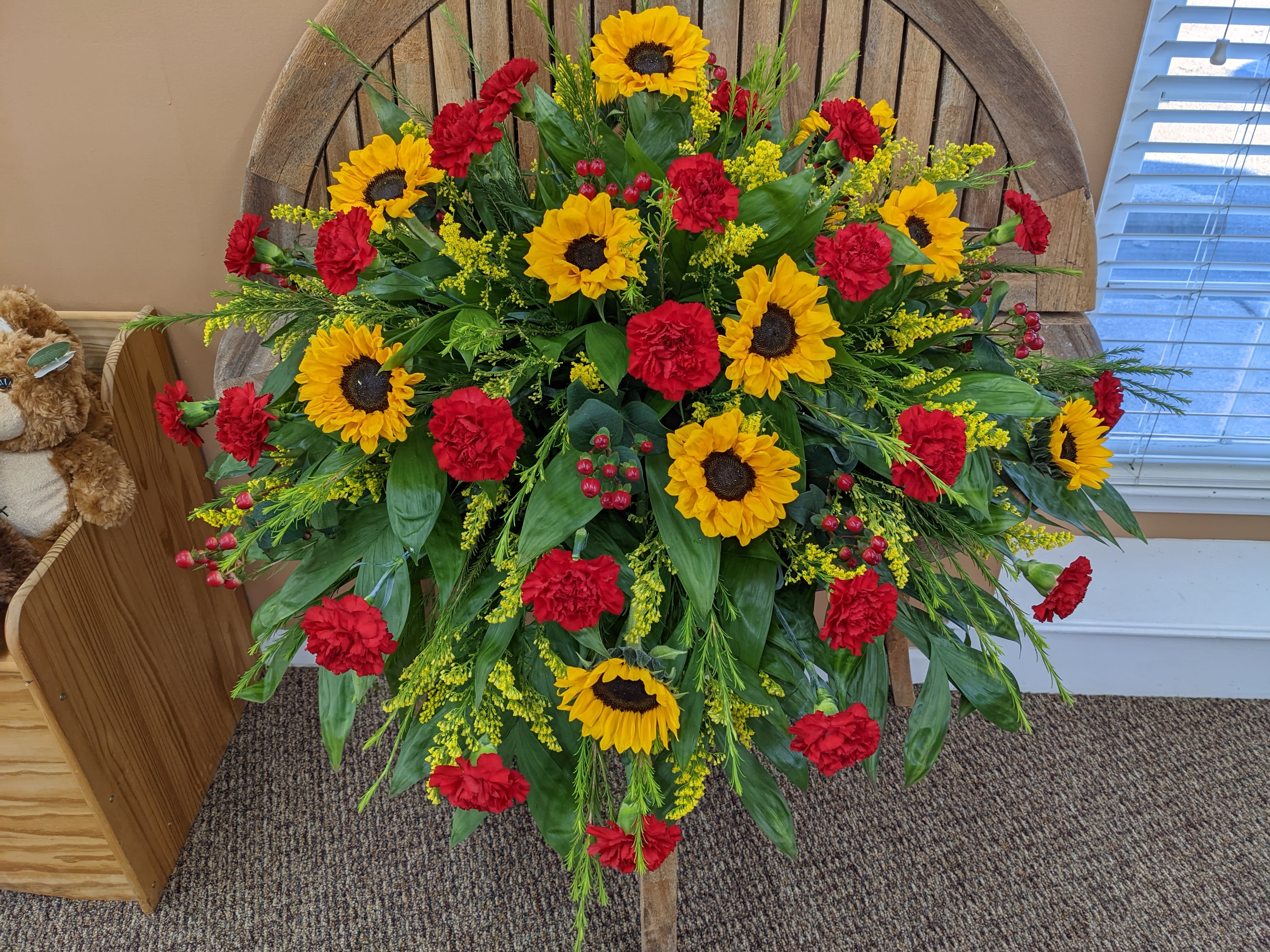 Large standing floral spray with sunflowers and red carnations