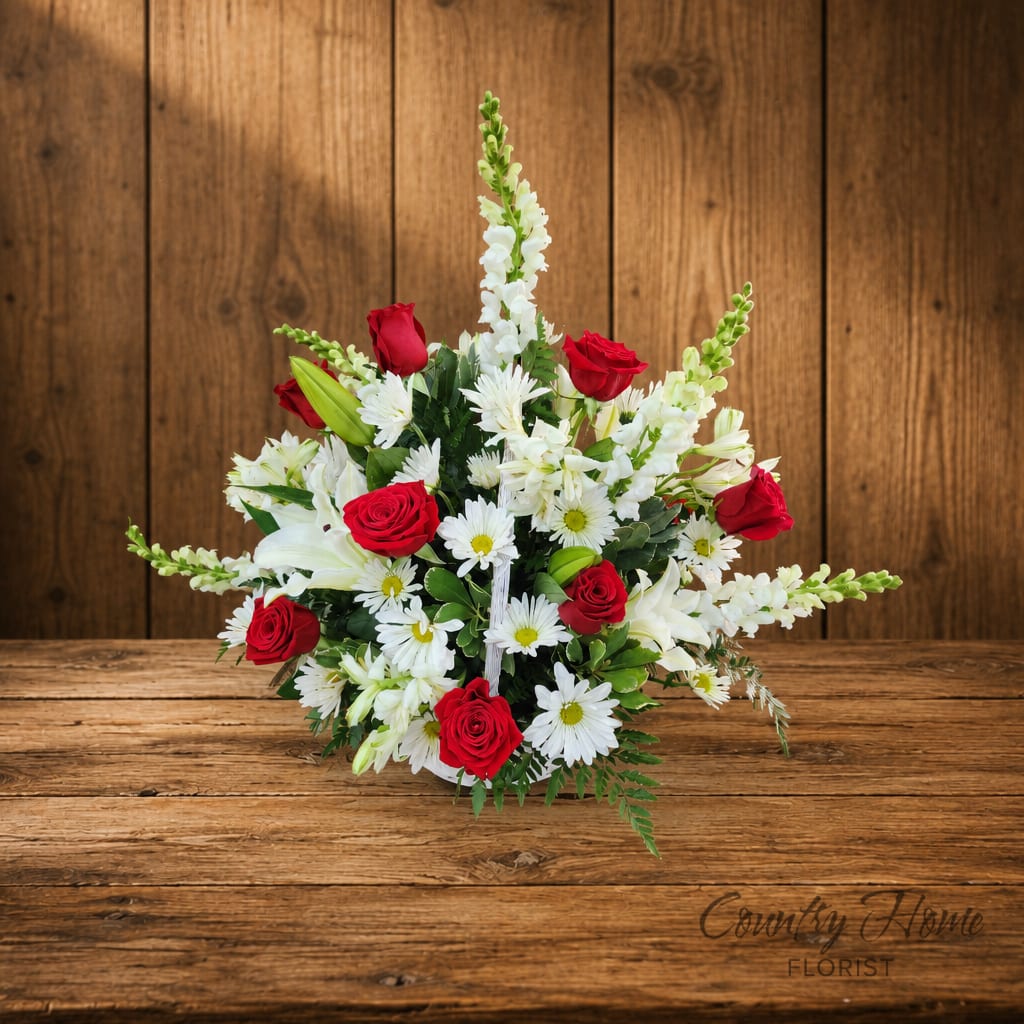 Bouquet of red roses and white daisies with white lilies in a low arrangement