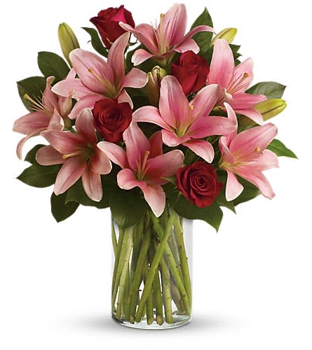 Pink lilies and red roses in a clear glass vase