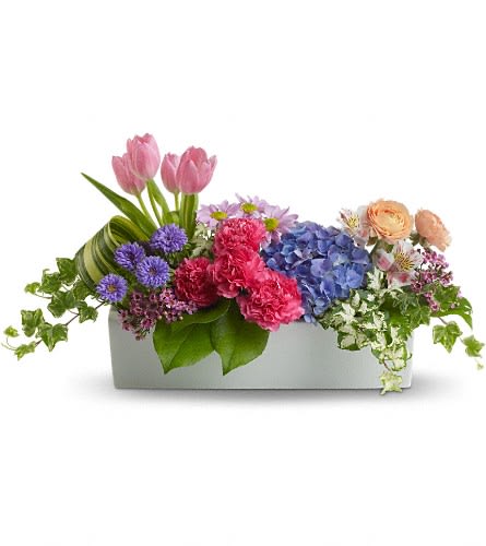 Mixed bouquet in a white rectangular container with pink tulips and blue hydrangea
