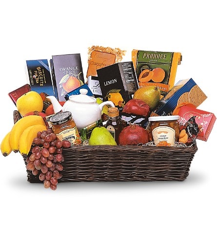 Gift basket with fruit, tea boxes, jam, and a teapot