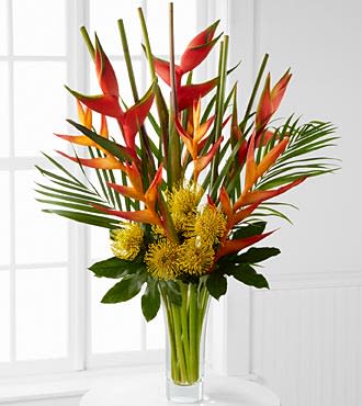 Striking Luxury Tropical Bouquet - LX114  Pull them into paradise with a flower bouquet of tropical blooms that will offer your special recipient a striking display of color and beauty. Yellow pincushion protea, stunning Birds of Paradise in both the psitticorum Heliconia psittacorum and upright Heliconia varieties, aralia leaves and areca palm are artistically arrnaged in a superior flared clear glass vase to create a flower arrangement set to bring exotic elegance to any of life's special celebrations. Includes: 6 stems of pincushion protea, 6 stems of psittacorum heliconia, 3 stems of upright heliconia, 3 stems of aralia leaves, 3 stems of areca palm, and a superior flared clear glass vase. Approximately 36"H x 28"W.