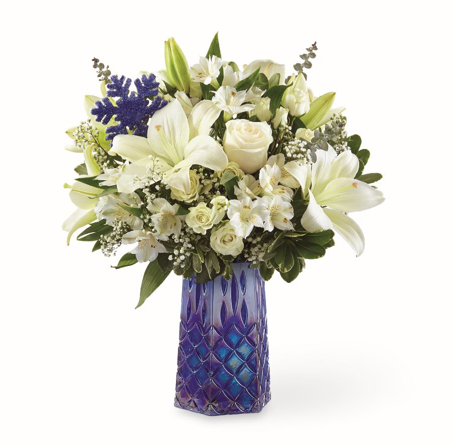 WINTER BLISS™ BOUQUET  - This iridescent blue glass vase with a debossed pattern and hexagonal shape effortlessly complements the white blooms and any holiday home it’s placed in. The shimmering blue snowflake adds the final seasonal touch.