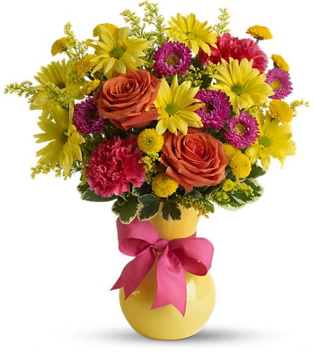 Bouquet of yellow daisies, orange roses, and pink flowers in a yellow vase with a pink ribbon