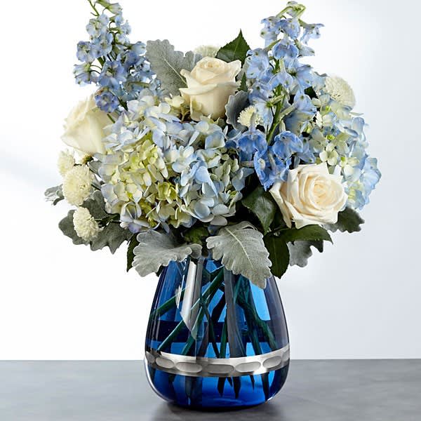 FTD Faithful Guardian Bouquet - An elegant blue crystal vase holds soft blue hues giving this arrangement a peaceful wintery look, perfect for every occasion!