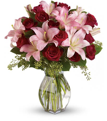 Bouquet of pink lilies and red roses in a clear glass vase