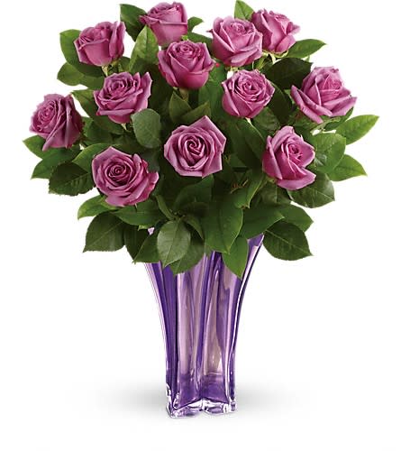 Purple roses arranged in a tall purple glass vase