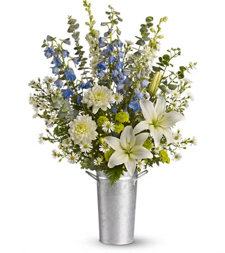 White lilies and blue flowers arranged in a tall metal vase