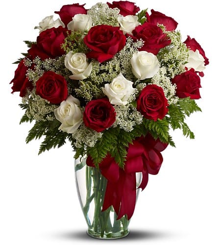 Bouquet of red and white roses in a clear glass vase with a red ribbon