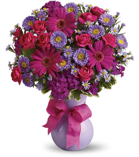 Pink and purple mixed flower bouquet in a lavender vase with a ribbon