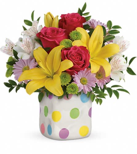 Bouquet of pink roses, yellow lilies, and daisies in a polka-dot vase