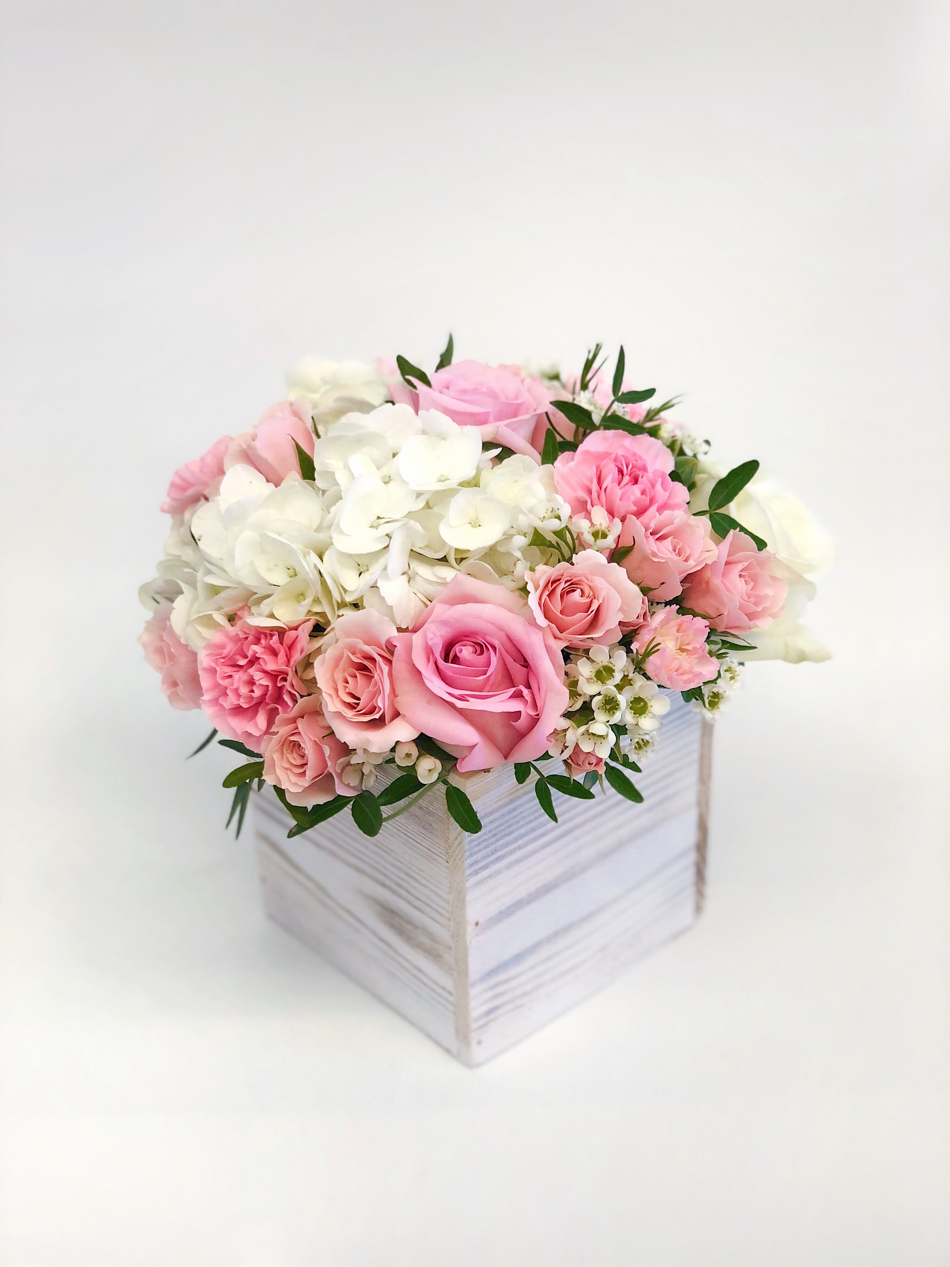 Pink and white roses with hydrangeas in a white wooden box