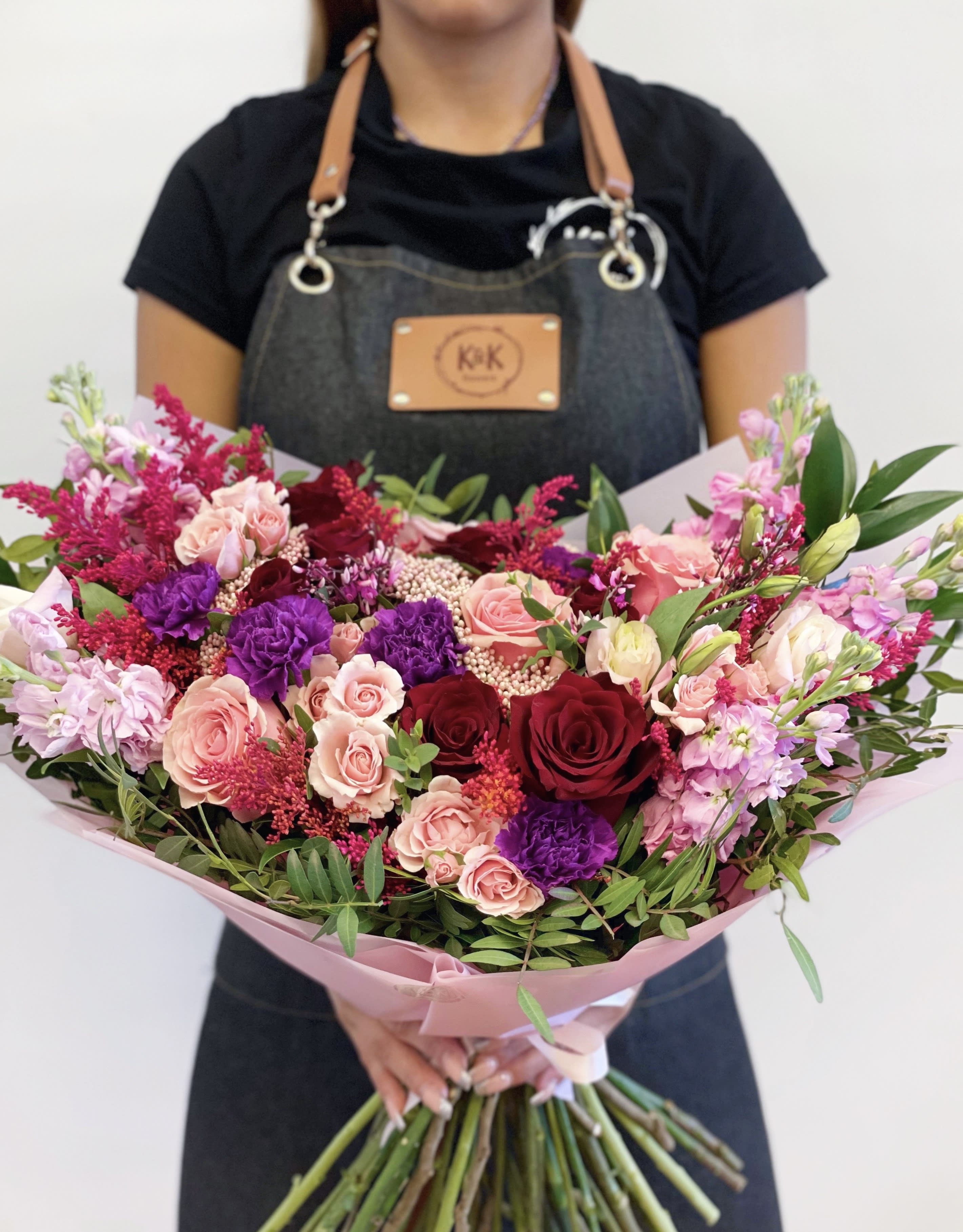 Large bouquet of pink, red, and purple flowers wrapped in pink paper