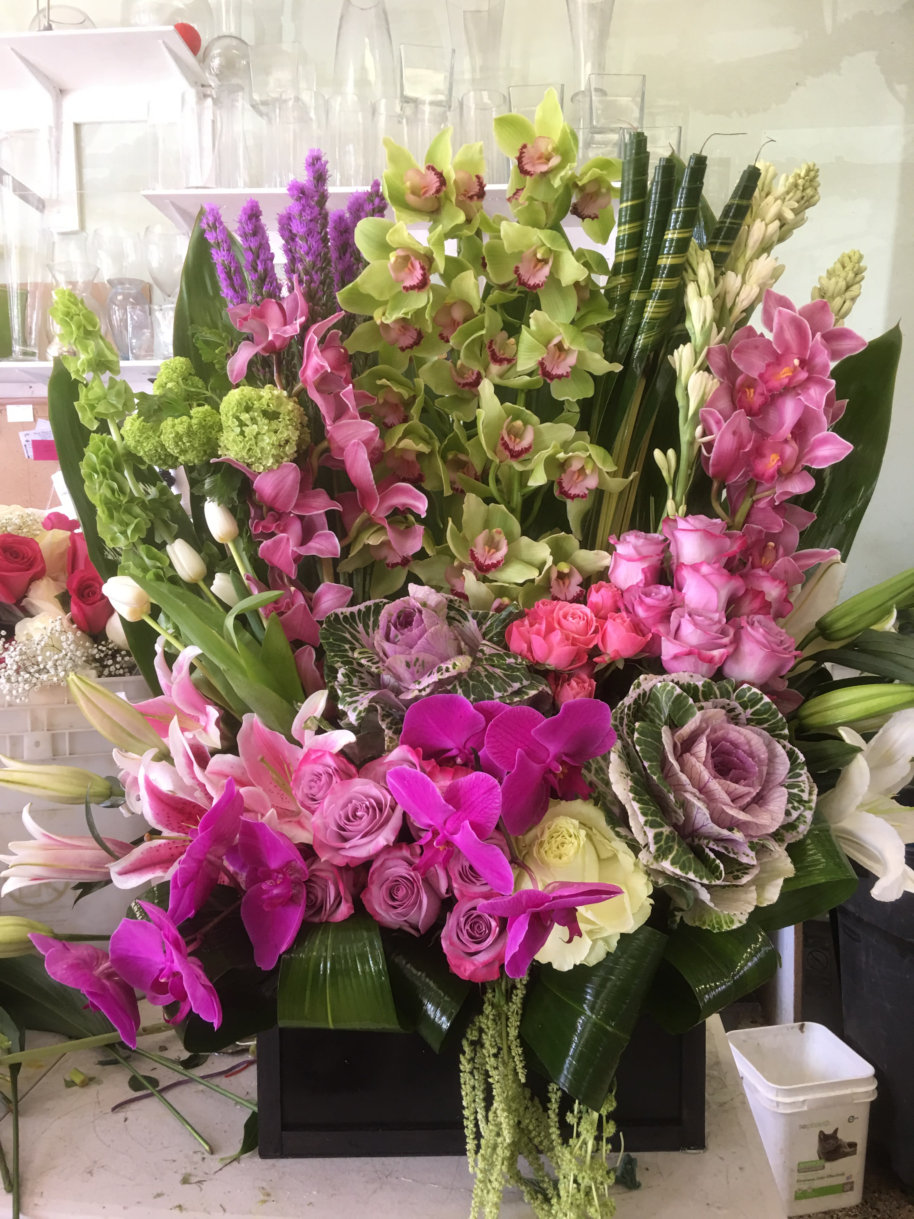 Large mixed floral arrangement with orchids, roses, lilies, and cabbage roses