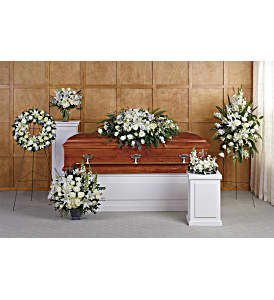 White funeral flowers arranged around a casket in a chapel setting