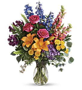 Mixed bouquet of roses, lilies, and snapdragons in a glass vase