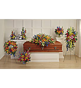 Colorful funeral casket spray with standing floral tributes