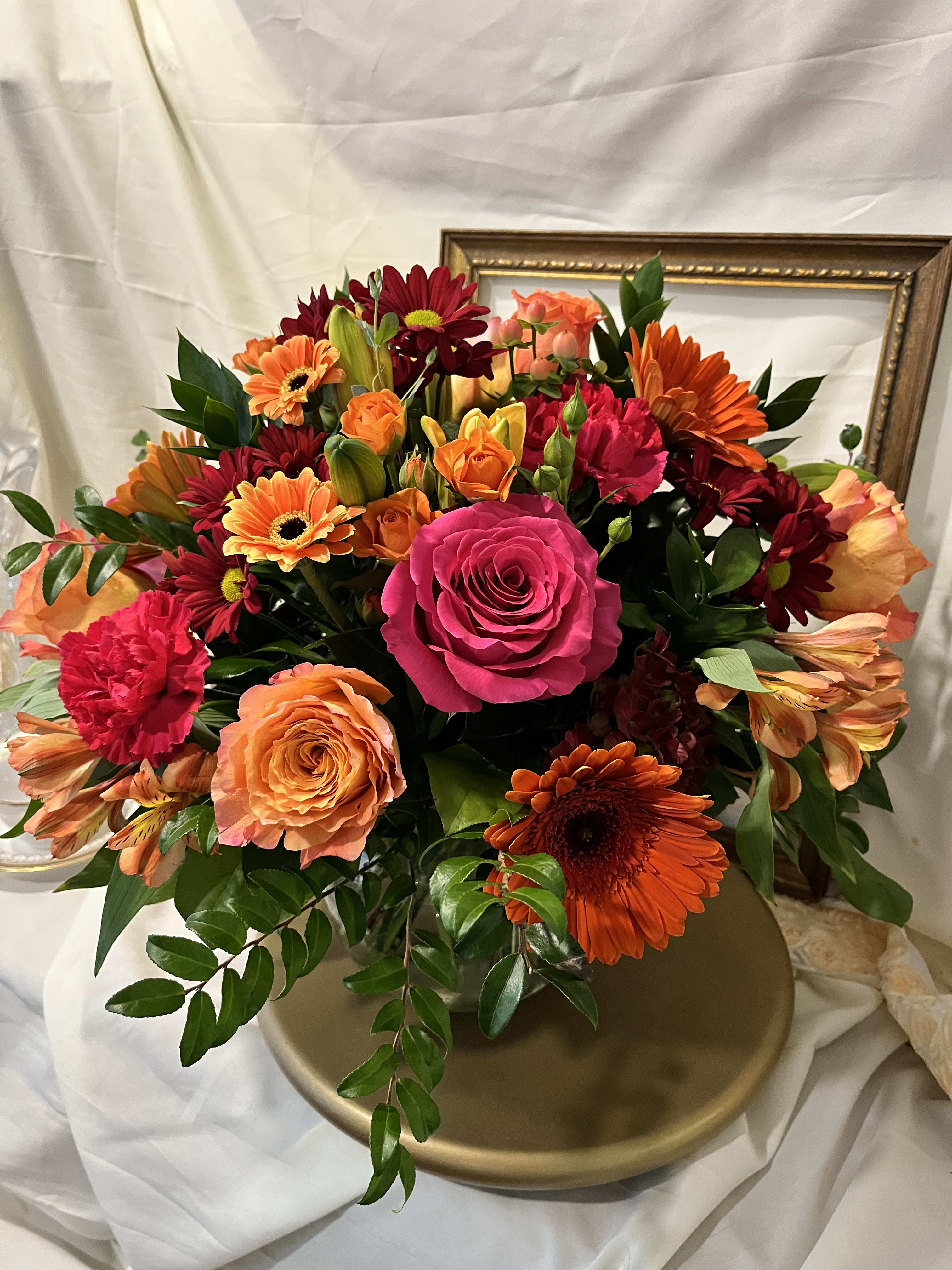 Mixed bouquet of roses, gerbera daisies, and carnations in warm pink, orange, and red tones