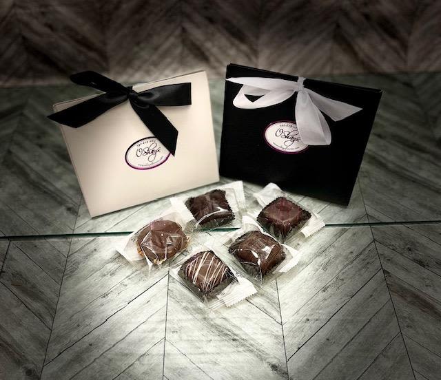 Two ribbon-tied gift boxes with wrapped chocolates on the floor
