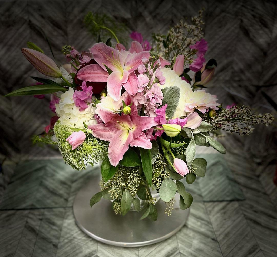 Pink lilies and white blooms arranged in a round bouquet