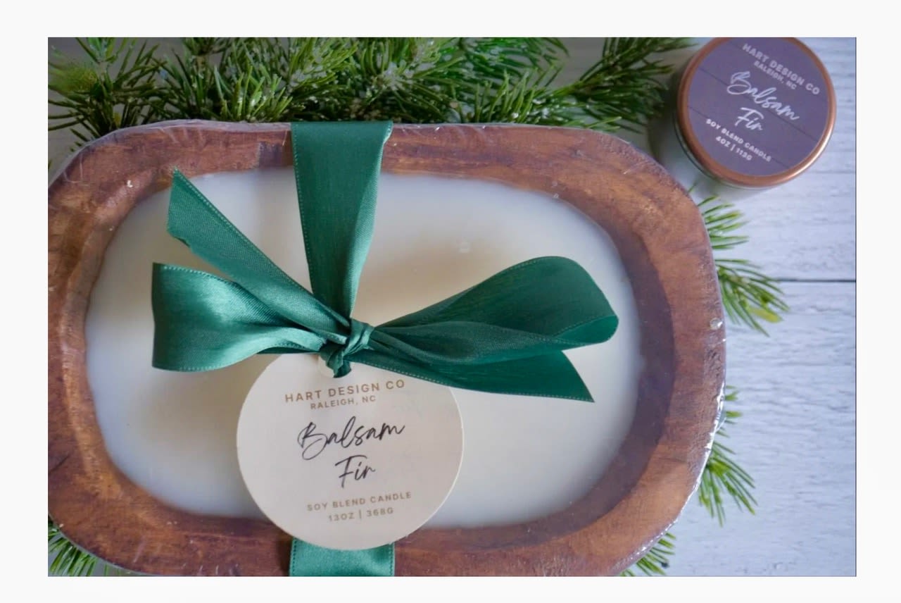 Soy candle in a wooden tray with a green ribbon and pine sprigs