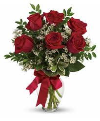 Bouquet of red roses with baby's breath in a glass vase tied with a red ribbon