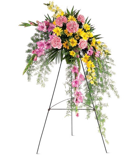 Standing floral spray with pink and yellow flowers on a black easel