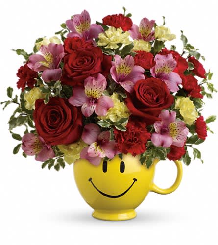 Bouquet of red roses and pink alstroemeria in a yellow smiley-face mug