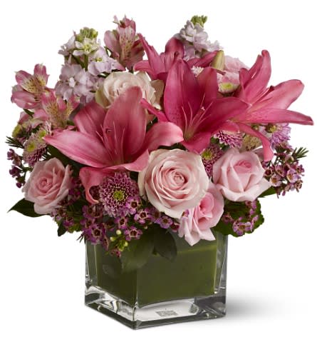 Pink lilies and roses arranged in a clear square vase