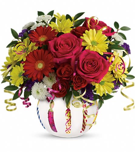 Mixed bouquet of roses and daisies in a white vase with curling ribbons