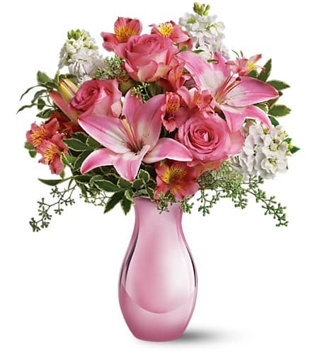 Pink roses and lilies arranged in a pink glass vase