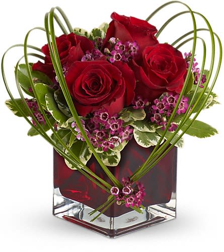 Red roses in a square glass vase with pink filler flowers
