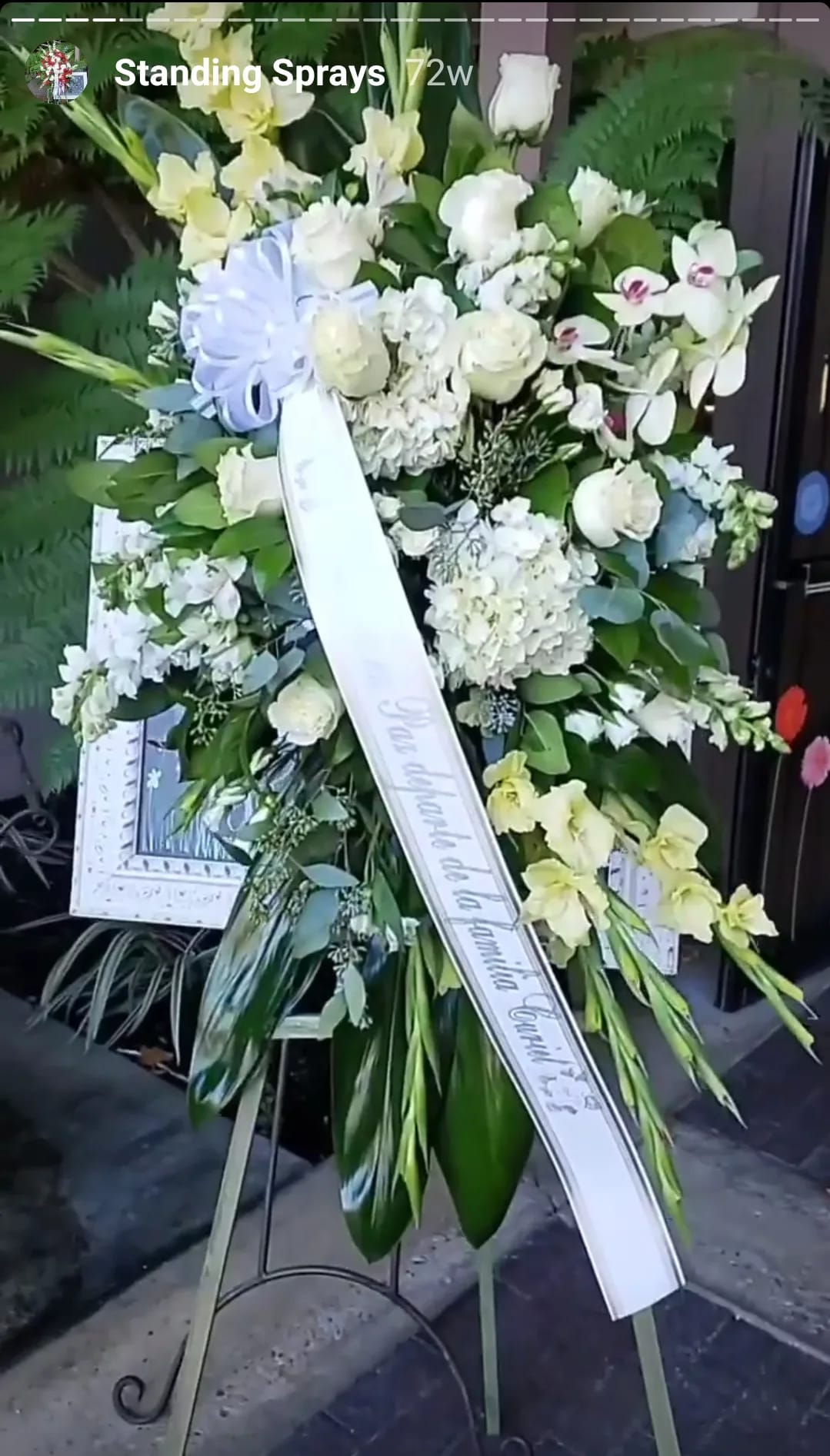 Standing funeral spray with white and pale yellow flowers on an easel
