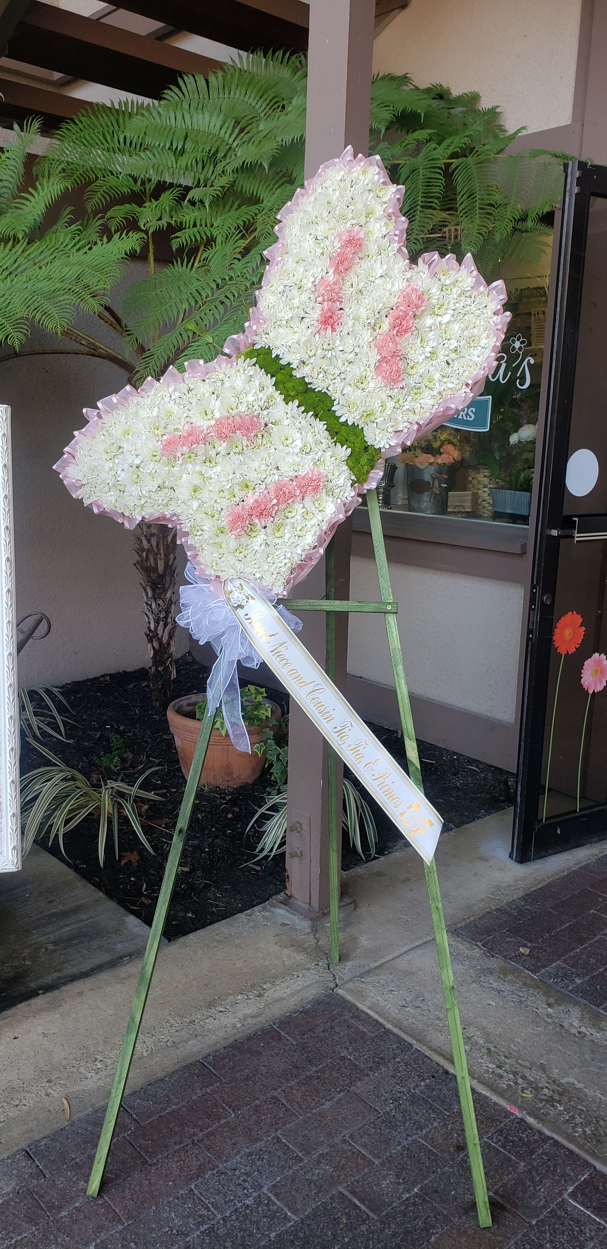 Heart-shaped standing floral tribute with white and pink flowers on an easel