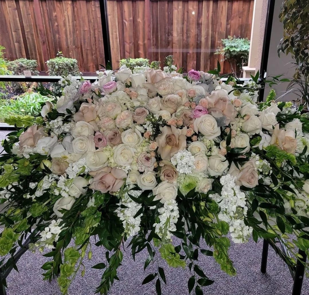 Large white and blush rose arrangement with trailing greenery