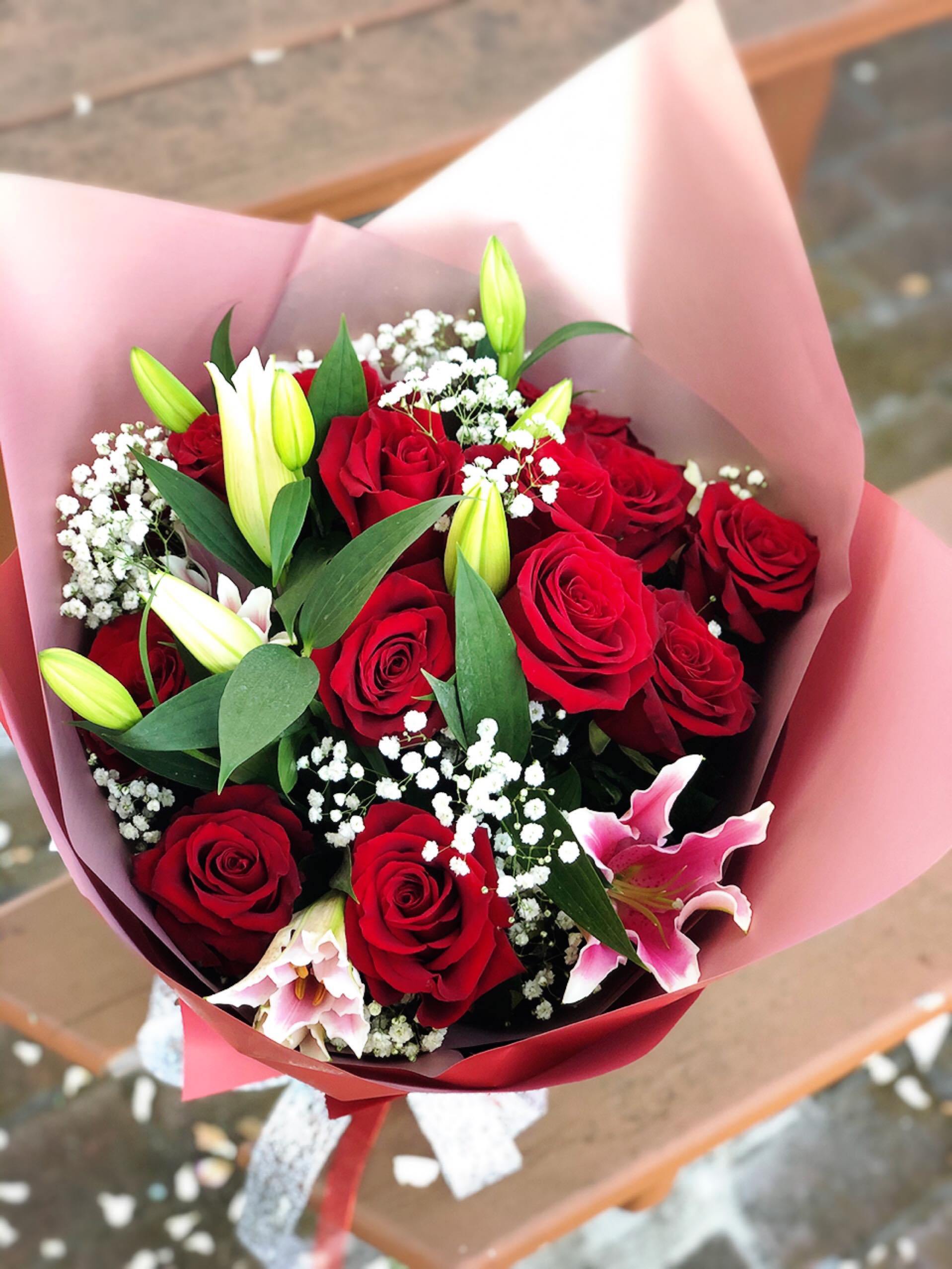 Bouquet of red roses and pink lilies wrapped in pink paper