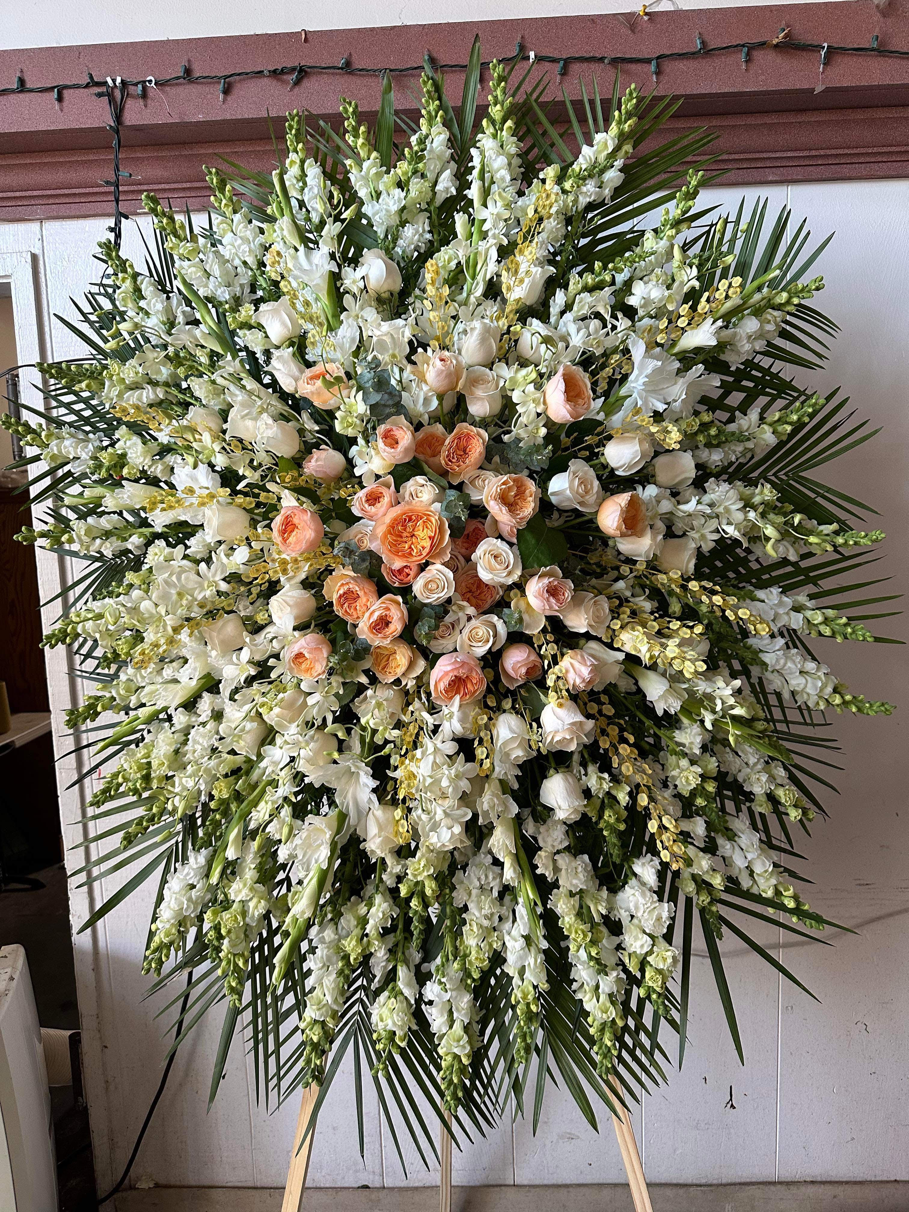 Large standing spray of white and peach roses with white blooms and palm fronds
