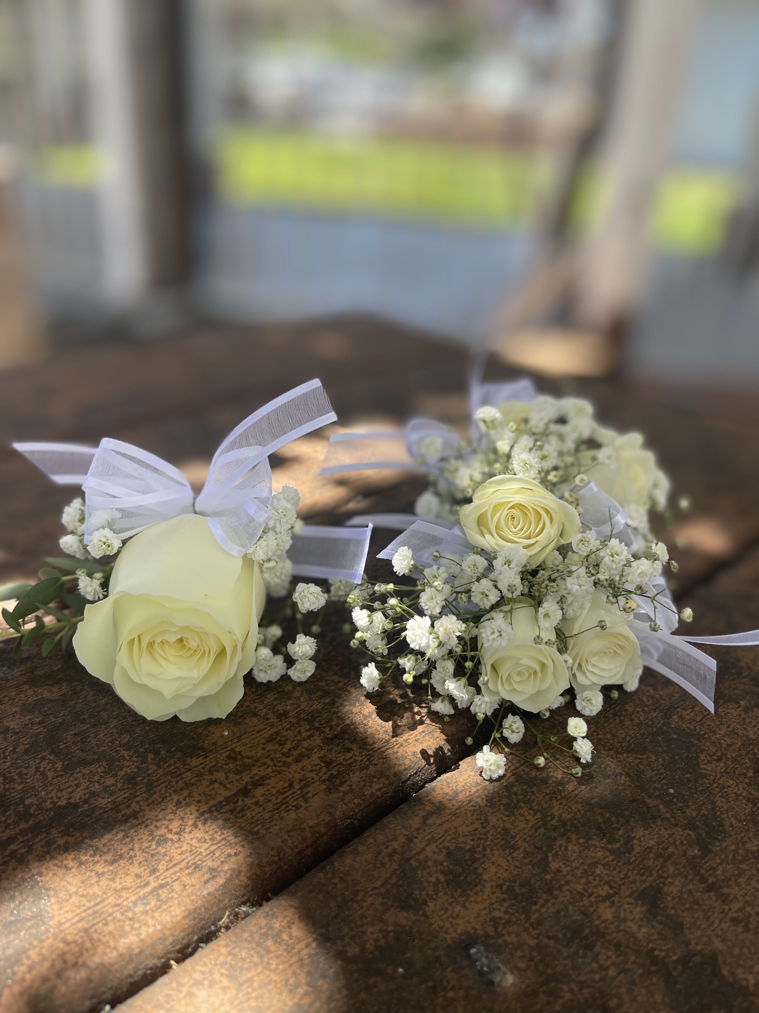 White rose boutonnieres with baby's breath and ribbon ties