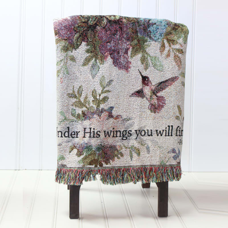 Decorative woven throw with hummingbirds and floral pattern draped over a chair