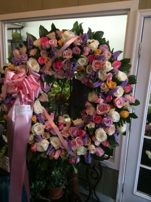 Large floral wreath of pink, white, and purple roses with a pink ribbon