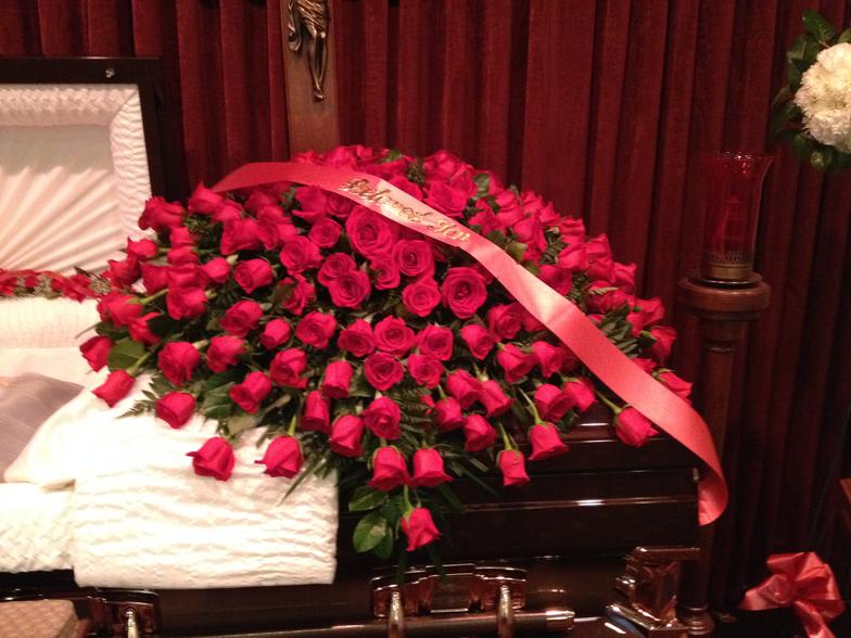 Large bouquet of red roses with a pink ribbon draped across it