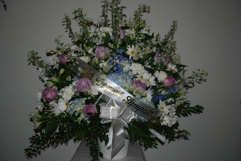 Large sympathy spray with pink roses, white daisies, and blue flowers