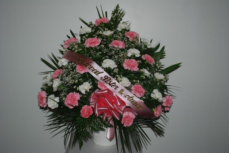Pink and white carnation funeral spray with a memorial ribbon