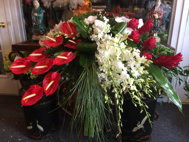 Large floral arrangement with red anthuriums and white orchids in black containers