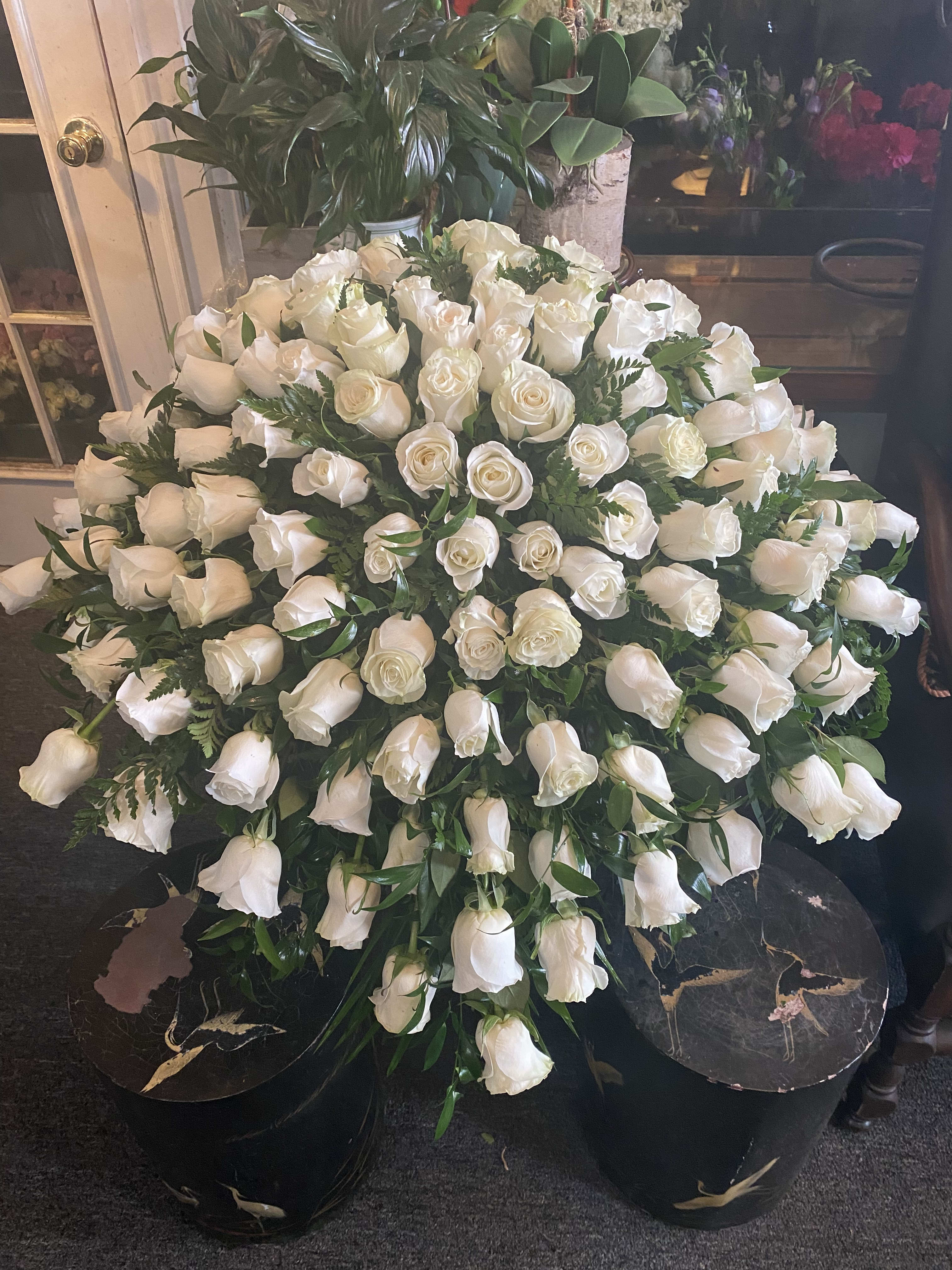 Large arrangement of white roses in a black container