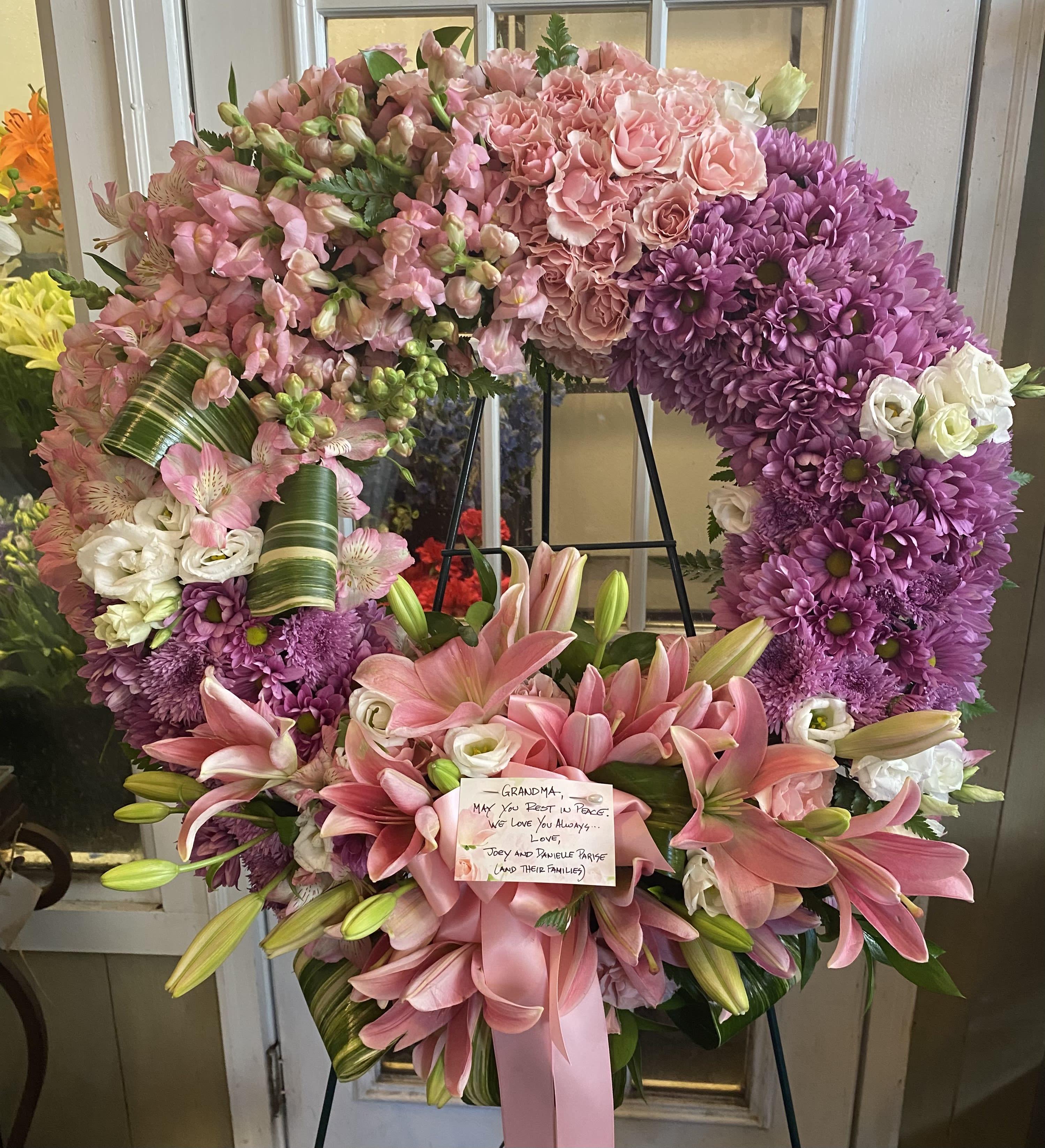 Large pink and purple funeral wreath with lilies and roses on an easel