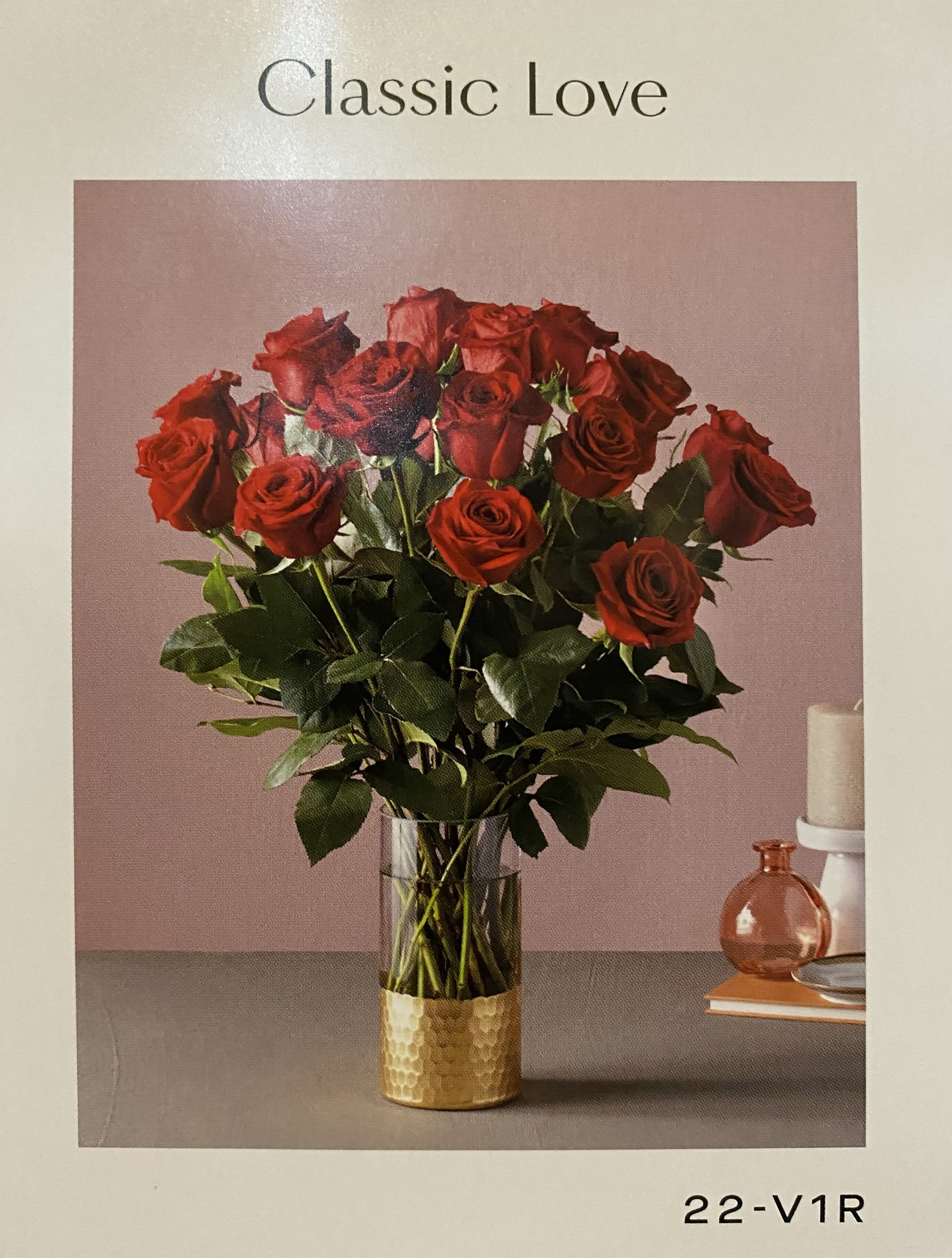 Red roses arranged in a clear vase with a gold base